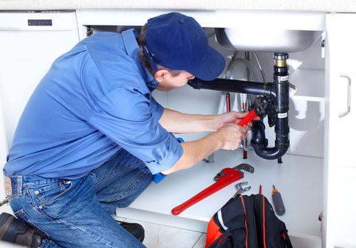 Local plumber repairing the P-trap under a kitchen sink in Richton Park, IL